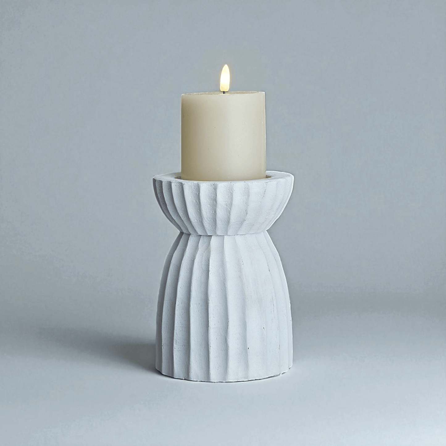 White carved hurricane lantern with candle, creating ambient lighting and patterned shadows for decoration.